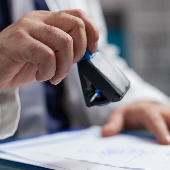 Hand of general practitioner using medical stamp on prescription paper